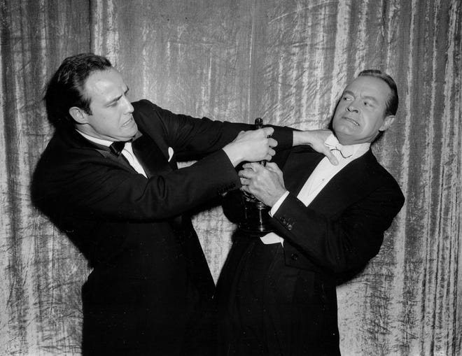 In this March 30, 1955 file photo, actor Marlon Brando, left, engages in a mock tussle with host Bob Hope during the 27th annual Academy Awards in Los Angeles. Brando won best actor for his performance in "On the Waterfront." Hope hosted or co-hosted 19 ceremonies, often joking that he never won one of the statuettes he was handing out. (AP Photo, File)