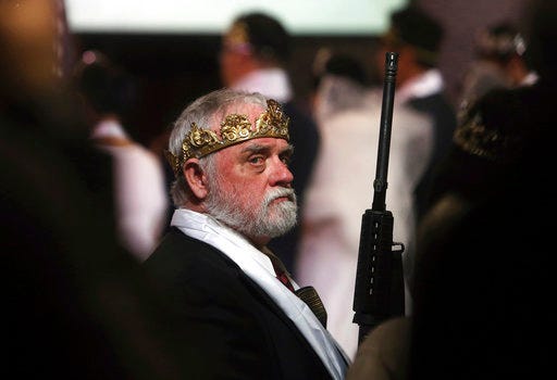 A man wears a crown and holds an unloaded weapon at the World Peace and Unification Sanctuary, Wednesday, Feb. 28, 2018, in Newfoundland, Pa. Worshippers clutching AR-15 rifles participated in a commitment ceremony at the Pennsylvania-based church. The event Wednesday morning led a nearby school to cancel classes for the day. The church's leader, the Rev. Sean Moon, said in a prayer that God gave people the right to bear arms. (AP Photo/Jacqueline Larma)