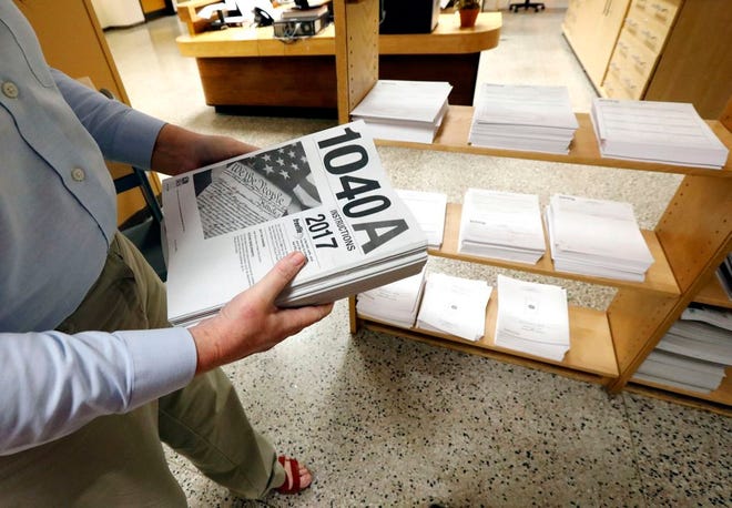 Susan Prendergast, reference supervisor at the Eudora Welty Library, in Jackson, Miss., adds additional federal tax filing information booklets on a shelf on Feb. 15, 2018. (AP Photo/Rogelio V. Solis, File)