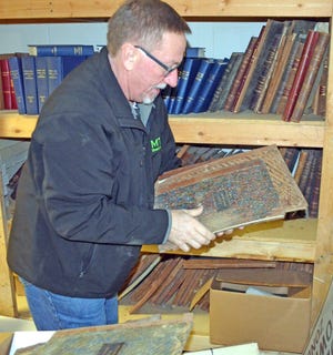 Coldwater Township Supervisor Don Rogers checks on historical records from the 1800s in the flooded township hall basement. DON REID PHOTO