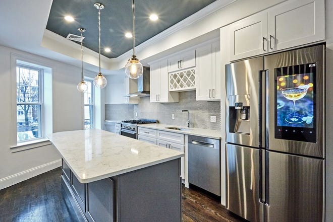 A study in contrasts, the dark hardwood floors are complemented by the 10-foot ceilings, white kitchen cabinets and counters, windows, warm paint colors, and chrome hardware and fixtures.