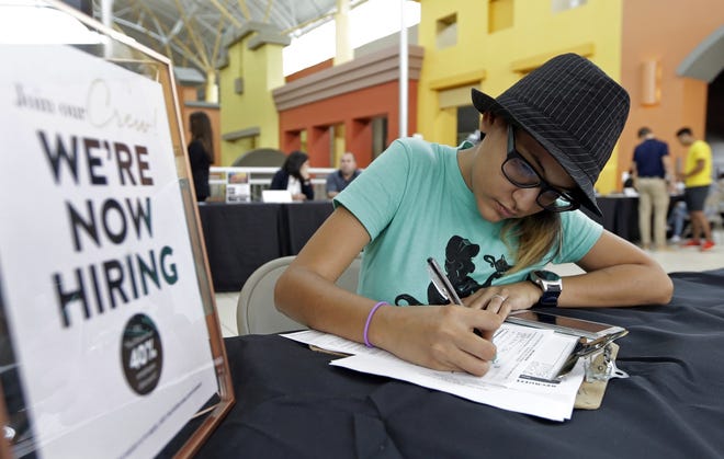 Job seeker Alejandra Bastidas fills out an application at a job fair in Sweetwater, Fla., in October 2017. U.S. workers' wages and benefits grew 2.6 percent last year, but nearly all of that growth was concentrated at the top and bottom of the wage scale. [AP file / Alan Diaz]