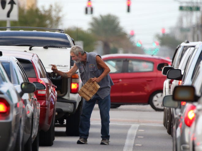 Panhandlers who boldly walk into traffic, like this man at International Speedway Boulevard and Ridgewood Avenue, can find themselves in police handcuffs or ticketed. Motorists and pedestrians are the focus of a safety campaign by Daytona Beach police. [News-Journal/Nigel Cook]