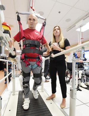 Derrik Amaral uses Cyberdyne's Medical Hybrid Assistive Limb -- or HAL -- device during a demonstration Friday at Brooks Rehabilitation with Jessica Dunn, Cyberdyne clinical coordinator, at his side. The technology is used in spinal cord rehabilitation. [BOB SELF/FLORIDA TIMES-UNION]