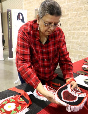 Lisa Rutherford sets out hand-beaded purses Friday, March 2, 2018, at her booth at the Fort Smith Convention Center for the Five Civilized Tribes Culture Festival on March 3, 2018, from 10 a.m. to 5 p.m. The festival features native American demonstrations, galleries and performances that include stomp dancing, singing, storytelling and lectures as well as traditional art sales, food and games demonstrations. The festival is part of the yearlong Fort Smith Bicentennial Celebration and is open and free to the public. [JAMIE MITCHELL/TIMES RECORD]