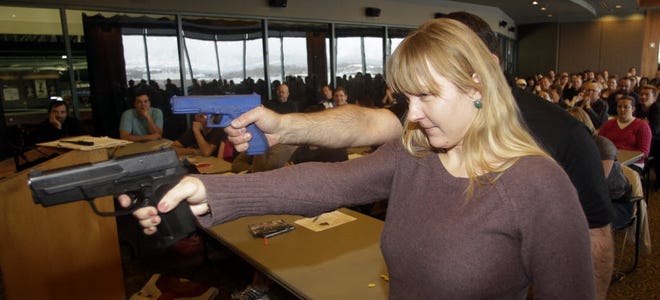 FILE PHOTO: In this Dec. 27, 2012, photo, Clark Aposhian, president of Utah Shooting Sport Council, demonstrates with a plastic gun, rear, while Joanna Baginska, 4th grade teacher from Odyssey Charted School, in American Fork, using a 40 cal. Sig Sauer during concealed-weapons training for the teachers. The Utah Shooting Sports Council offered six hours of training in handling concealed weapons in the latest effort to arm teachers to confront school assailants.