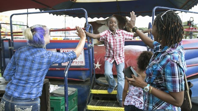 RODEO NOW: More recent attractions include a mechanical bull ride, ridden in 2016 by Gabriel McMillan. He was congratulated by his mother, Joselyn McMillan, right, sister Logan and ride operator Shianna Dockins, left. RALPH BARRERA/ AMERICAN-STATESMAN