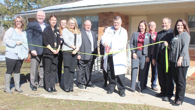 Troy Davis, D.O. at ProMedica’s Litchfield Clinic snips a ceremonial ribbon signifying the completion of renovations at the office in Litchfield on Friday. He was joined by staff, ProMedica administration and Litchfield Mayor O.R. Smith. [ANDREW KING PHOTO]