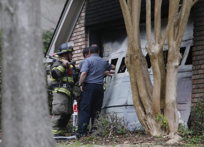 Firefighters with Tuscaloosa Fire and Rescue Service take measurements through a blown out window of a garage in the Covey Chase neighborhood after extinguishing a fire just after 2:50 p.m. on Monday afternoon. The garage was fully involved when firefighters arrived on scene. Three fire trucks, a ladder truck, a rescue truck, and the battalion chief responded to the fire. [Staff Photo/Erin Nelson]