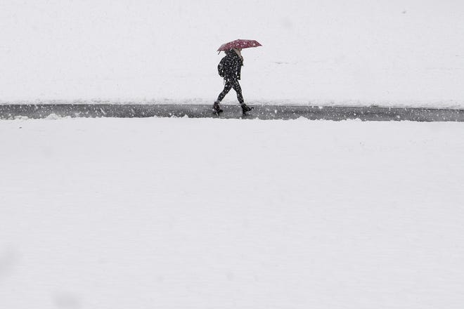 A pedestrian shields herself from the snow with and umbrella as she walks through campus grounds at Swarthmore College on Wednesday in Swarthmore, Pa. [Jose F. Moreno/The Philadelphia Inquirer]