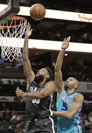 Brooklyn Nets' Allen Crabbe, left, slips past Hornets' Nicolas Batum to get off a shot during the first half of Thursday night's game in Charlotte, N.C. [The Associated Press]