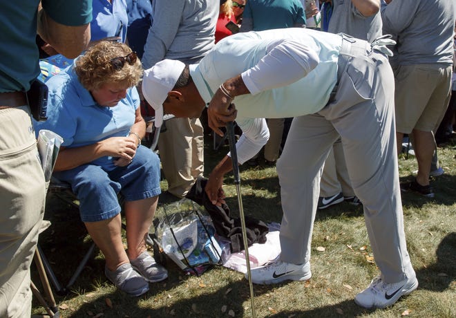 Tiger Woods reaches into a fan's bag after his approach shot on the ninth hole landed in it during the second round of the Valspar Championship in Palm Harbor, Fla. [The Associated Press]