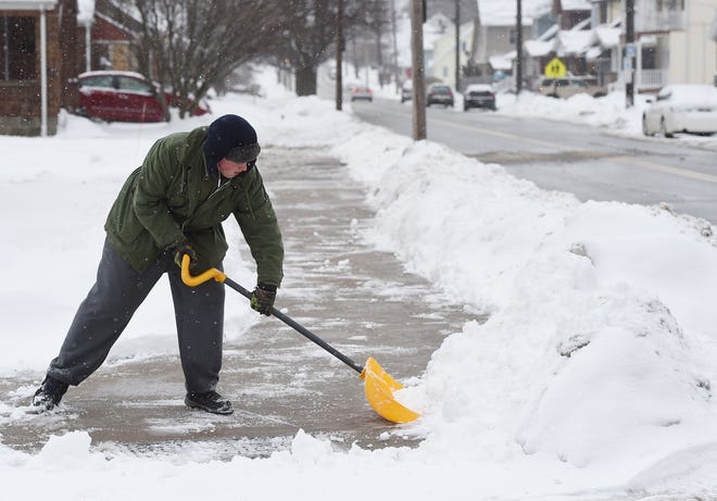 Connor Allessie, 19, of Erie, shovels snow at the corner of West 32nd and Plum streets in Erie on Friday. The late-week storm has Erie fewer than 13 inches away from breaking the 200-inch mark for seasonal snowfall. [JACK HANRAHAN/ERIE TIMES-NEWS]