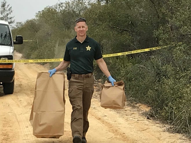 Sgt. Keith Miller with the Marion County Sheriff's Office carries evidence gathered from a crime scene Saturday in the Ocala National Forest. [Austin L. Miller/Staff]