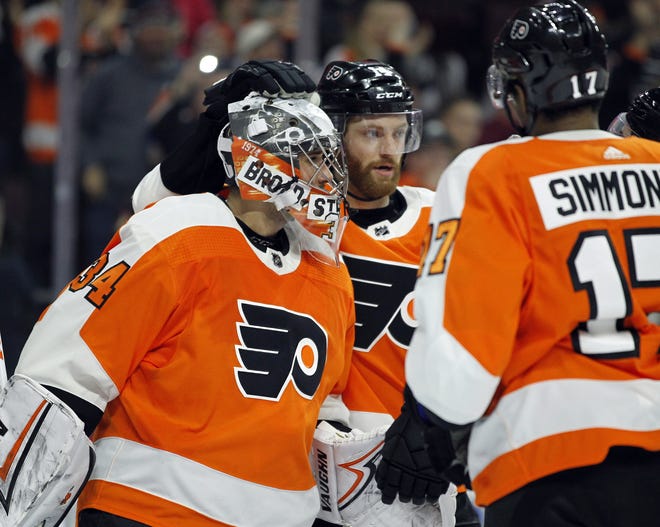 Philadelphia Flyers goalie Petr Mrazek, left, and Sean Couturier, center, and Wayne Simmonds celebrate their 2-1 win over the Winnipeg Jets with teammates at the end of a NHL game on Saturday in Philadelphia. [AP Photo/Tom Mihalek]