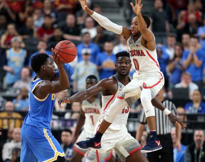 UCLA's Aaron Holiday, left, looks to pass while defended by Arizona's Parker Jackson-Cartwright (0) during overtime of an NCAA college basketball game in the semifinals of the Pac-12 men's tournament last Friday in Las Vegas. The Bruins have to earn the chance to face Florida (20-12) on Thursday in Dallas as part of the East region. [AP Photo/Isaac Brekken]