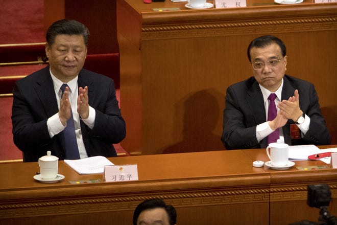 Chinese President Xi Jinping and Premier Li Keqiang applaud during a plenary session of China's National People's Congress (NPC) at the Great Hall of the People in Beijing on Sunday. China's rubber-stamp lawmakers on Sunday passed an historic constitutional amendment abolishing presidential term limits that will enable President Xi Jinping to rule indefinitely. [Mark Schiefelbein/The Associated Press]