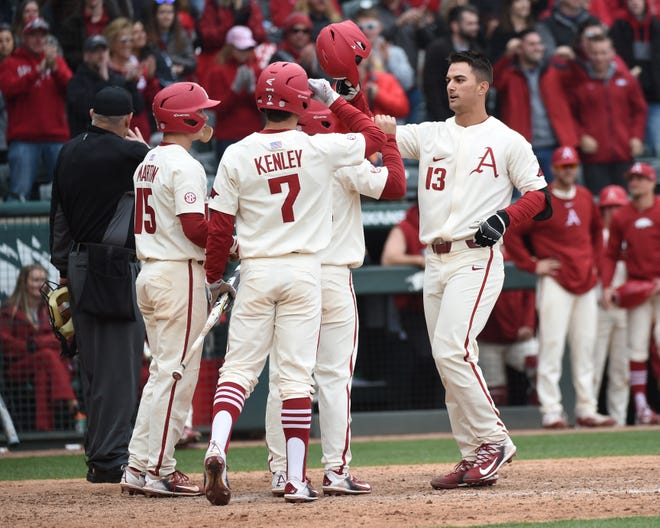 Razorback sophomore first baseman Jordan McFarland (#13) celebrates a grand slam with his teammates, sophomore pinch-runner Jack Kenley (#7) and freshman third baseman Casey Martin (#15), on Sunday, March 11, 2018, at Baum Stadium. The Hogs beat the Golden Flashes from Kent State 11-4 to take the series 2-1. McFarland had 2 HRs with 5 RBIs while going 2-3 at the plate. [CRAVEN WHITLOW/SPECIAL TO NATE ALLEN SPORTS SERVICE]