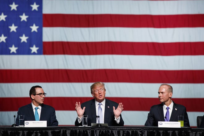 Treasury Secretary Steve Mnuchin, left, and Boeing CEO Dennis Muilenburg, right, listen as President Donald Trump speaks during a roundtable discussion on tax policy at the Boeing Company on Wednesday in St. Louis. [Evan Vucci/The Associated Press]