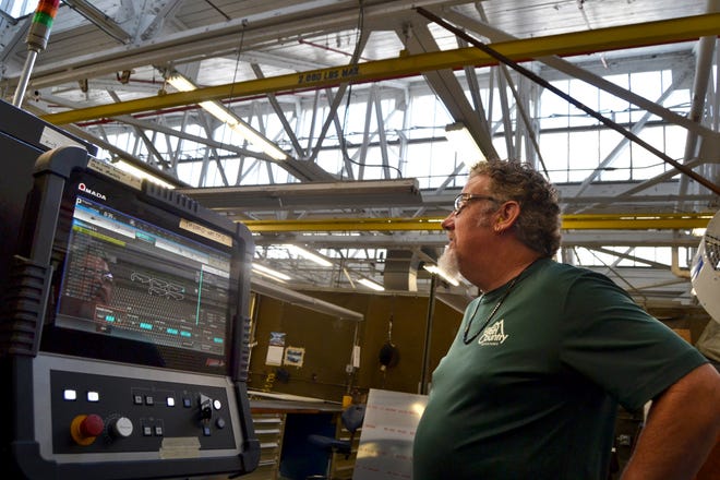 Sheet metal mechanic John Montgomery watches the progress of Fleet Readiness Center Southeast's new fiber laser cutter on the machine's monitor.