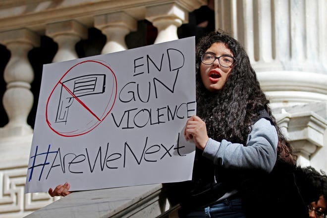 Navyerlin Metivier, 15, a freshman at Hope High School, holds a sign inside the State House during Wednesday's rally. [The Providence Journal / Glenn Osmundson]