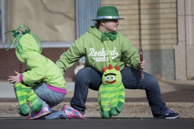 Sophie Cross, left, and her sister, Emily, grab candy from the street March 11, 2017, during the St. Patrick's Day Parade in Rockford. [MAX GERSH/RRSTAR.COM]