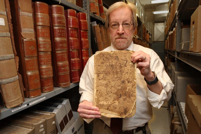 Stephen Grimes, director of State Archives, holds a minute book from the Rhode Island Colonial courts in 1746. [The Providence Journal / Steve Szydlowski]