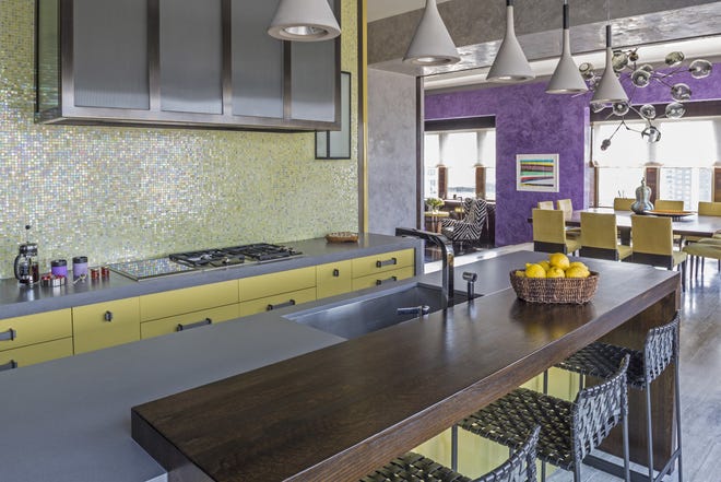 This Tribeca kitchen, designed by Drake/Anderson, flows seamlessly into the main living space. Repeating touches of color run throughout the rooms, echoing the mosaic backsplash pattern in the chair upholstery. The flooring also runs from the kitchen to the main living space. [Marco Ricca/Drake/Anderson via AP]