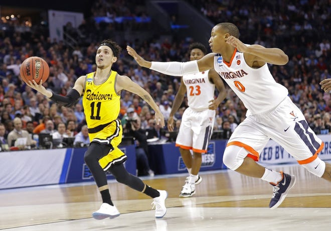 UMBC's K.J. Maura (11), a former junior college All-American at the College of Central Florida in Ocala, drives past Virginia's Devon Hall (0) during the second half of the Retrievers' 74-54 win over the nation’s top-ranked team in a first-round game of the NCAA men's college basketball tournament Friday in Charlotte, N.C. [AP Photo/Gerry Broome]