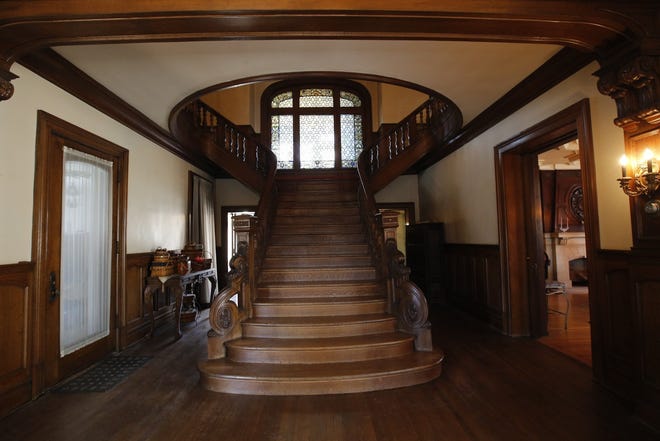 The center hall of the 1910 mansion on East Broad Street features a staircase that rises to a landing with a grand stained-glass window. [Tom Dodge/Dispatch]