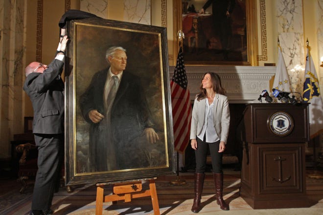 Randall Rosenbaum, of the Rhode Island State Council On The Arts, unveils the portrait in January 2015 of former Gov. Lincoln Chafee as artist Julie Gearan, of Providence, watches. [The Providence Journal / Steve Szydlowski]