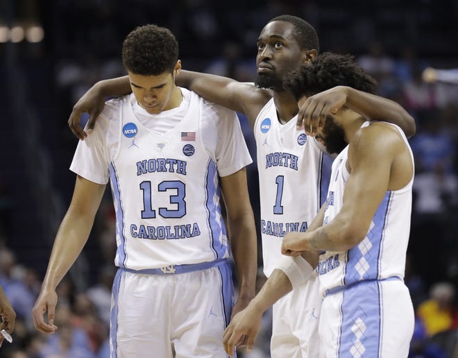 North Carolina players, from left, Cameron Johnson, Theo Pinson and Joel Berry II embrace in the final minutes of the Tar Heels' loss to Texas A&M on Sunday in the second round of the NCAA Tournament in Charlotte. It was the final college game for Pinson and Berry. [Gerry Broome/The Associated Press]