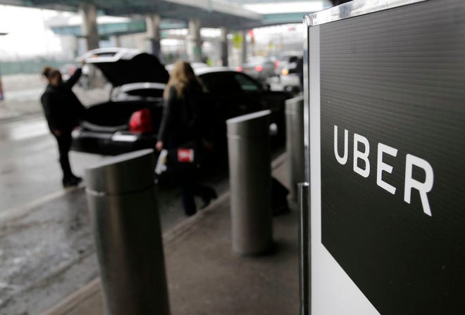 In this March 15, 2017, file photo, a sign marks a pick-up point for the Uber car service at LaGuardia Airport in New York.