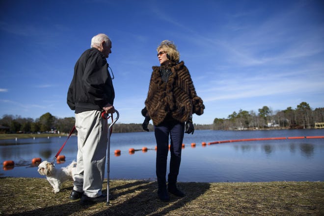 Mac McHenry, left, and wife Sunday look at the newly filled Hope Mills lake and completed dam with their dog Jazzy on January 31, 2018. "It's prettier than it's ever been", said long time resident Sunday.[Melissa Sue Gerrits/The Fayetteville Observer]