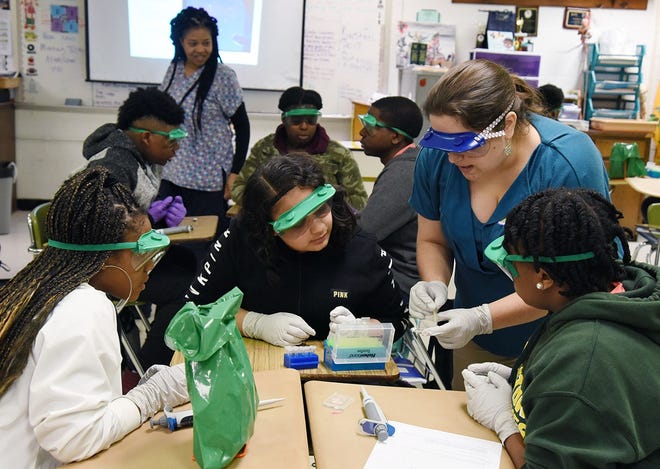 Bethany Kenyon of Bionetwork works with biomedical technology students at Kinston High School on Tuesday in an exercise designed to acquaint them with lab skills associated with DNA analysis. Teacher Crystal Payton-Demry is in the background. [Submitted photo]