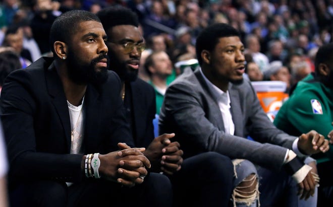 Kyrie Irving, left, sits with teammates Jaylen Brown, center, and Marcus Smart during the first quarter of Tuesday night's game.