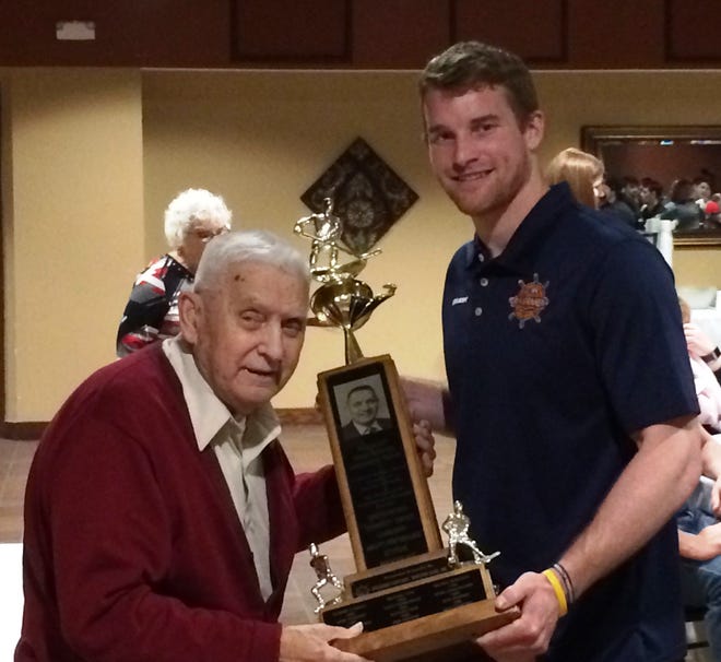 DAVE EMINIAN/JOURNAL STAR Peoria Rivermen winger Alec Hagaman holds the Mark Olson Award, while the trophy's namesake assists, at a Rivermen Booster Club banquet on Wednesday.