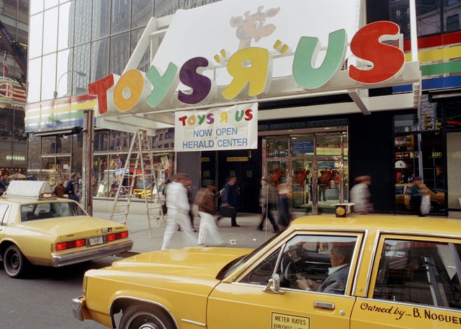 Pedestrians pass under the Toys R Us marquee in New York before the grand opening. The company will liquidate all of its U.S. stores. [AP Photo/Richard Drew, File]