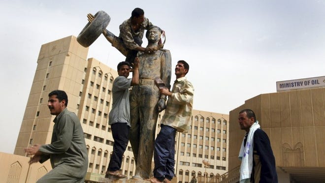 Iraqis prepare to tear down a statue of Saddam Hussein in front of the Ministry of Oil as they celebrate the arrival of Americans in Baghdad on April 9, 2003. (Tyler Hicks/The New York Times)