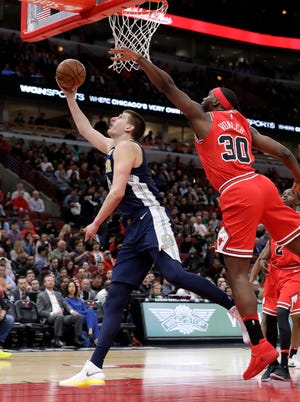 Denver Nuggets' Nikola Jokic, left, scores past Chicago Bulls' Noah Vonleh during the first half of an NBA basketball game Wednesday, March 21, 2018, in Chicago. (AP Photo/Charles Rex Arbogast)
