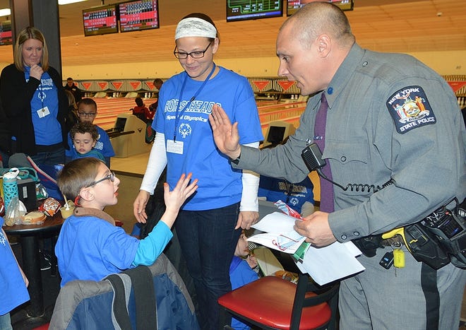 State Trooper Chris Glick handed out ribbon and high fives to the bowlers at the Special Olympics Bowling event Wednesday at Crystal Lanes in Corning. [ERIC WENSEL/THE LEADER]