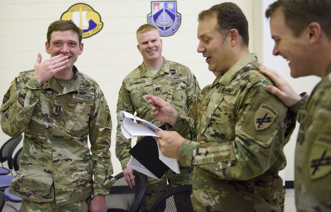 Capt. Kevin Moore, left, and Maj. Leo Poveda, third from left, read peer evaluations after a ceremony marking their graduation from the John F. Kennedy Special Warfare Center and School on Friday. This year marks the 100th anniversary of the Civil Affairs service. [Melissa Sue Gerrits/The Fayetteville Observer]