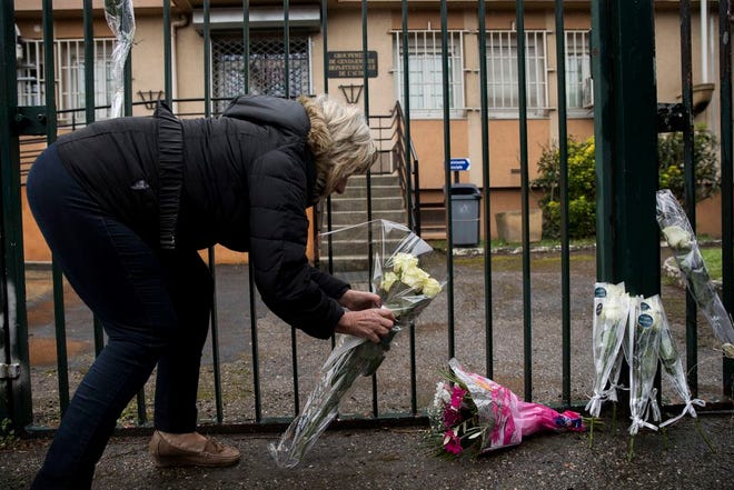 A woman places flowers at the main gate of the Police headquarter in Carcassonne on Saturday, following an attack on a supermarket in the south of France on Friday. A French police officer who offered himself up to an Islamic extremist gunman in exchange for a hostage died of his injuries, raising the death toll in the attack to four, and the officer was honored Saturday as a national hero of "exceptional courage and selflessness."