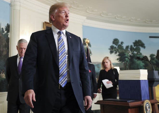 President Donald Trump stops to answers questions from the media after speaking in the Diplomatic Room of the White House in Washington on Friday, March 23, 2018, about the $1.3 trillion spending bill. With him are Defense Secretary Jim Mattis, left, and Homeland Security Secretary Kirstjen Nielsen. [AP Photo/Pablo Martinez Monsivais]
