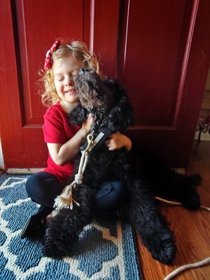Lillie Bridges, 4, hugs service dog Cooper while at their home in Polkville on Friday. Lillie was diagnosed with type one diabetes last May, and Cooper is in training to help manage the condition. [Brittany Randolph/The Star]