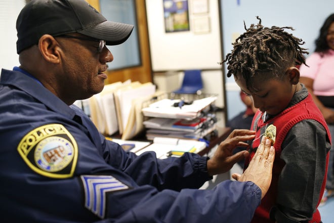 Watkinsville Police Detective Sgt. Will Horton puts a policeman badge sticker on 6-year-old King David Pitts whose life he saved. [Joshua L. Jones/Athens Banner-Herald]