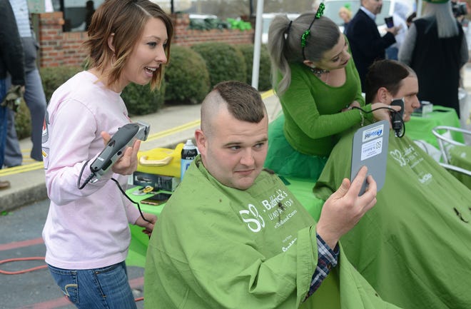 Ashley Humphrey stops shaving Chase Reese's head so he can take look as his participates in the St. Baldrick's Foundation's Rock the Bald to conquer childhood cancers head shaving event Tuesday at East Coast Wings. [Janet S. Carter / The Free Press]