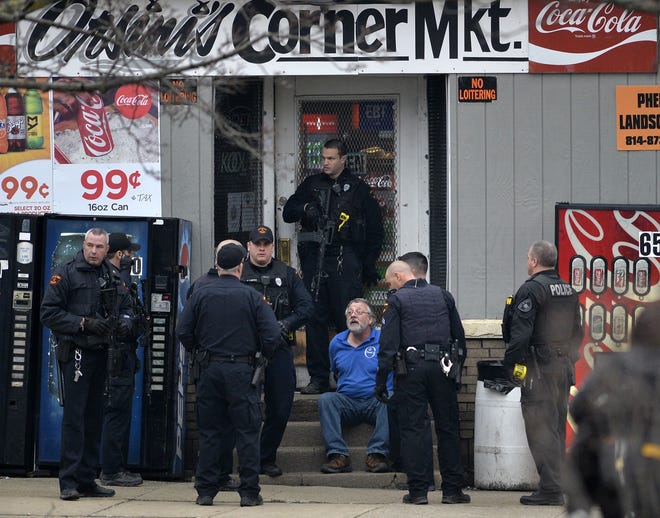 Erie Bureau of Police officers surround and question a suspect outside Orsini's Corner Market on Wednesday. [GREG WOHLFORD/ERIE TIMES-NEWS]