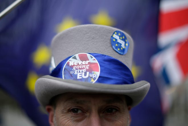 FILE - In this Monday, Feb. 5, 2018 file photo, demonstrators opposing Brexit wave flags as European Union chief Brexit negotiator Michel Barnier meets at 10 Downing Street in London. Such was the shock that some 52 percent voted to leave the EU, that the government was hardly prepared for quick negotiations with Brussels. (AP Photo/Tim Ireland, File)