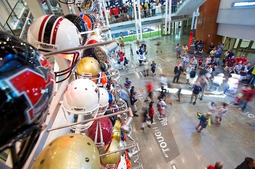 FILE - In this Aug. 23, 2014, file photo, visitors walk through the lobby of the College Football Hall of Fame after its grand opening, Saturday in Atlanta. Peach Bowl president Gary Stokan says he still sees the College Football Hall of Fame as the hub of Atlanta’s claim as the “capital of college football,” and his bowl has invested another $8 million in that vision. The Peach Bowl on Thursday, March 29, 2018, extended its partnership with the Hall of Fame for 10 years with the new investment which followed the original $5 million commitment when the hall opened in 2014. (AP Photo/David Goldman, File)
